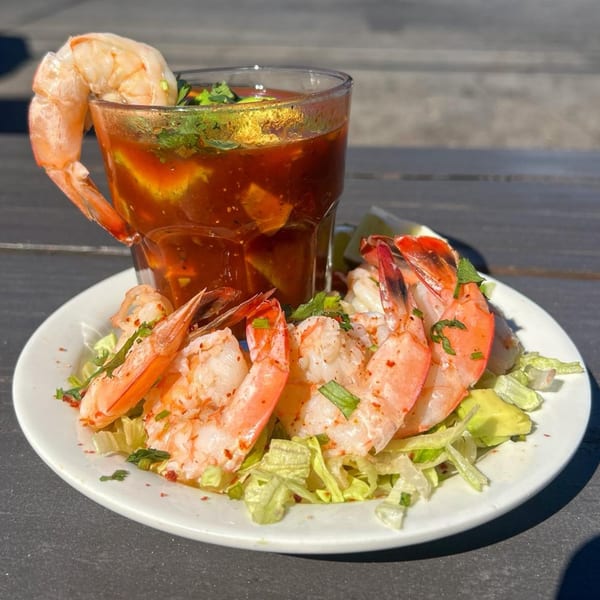 Shrimp cocktail with a large glass of red sauce, garnished with cilantro and lime.